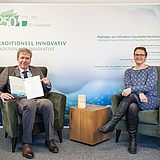 Prof. Degner und Präsidentin Dr.-Ing. Slyvia Schattauer sitzen in Sesseln vor der Fotowand der TU Clausthal.