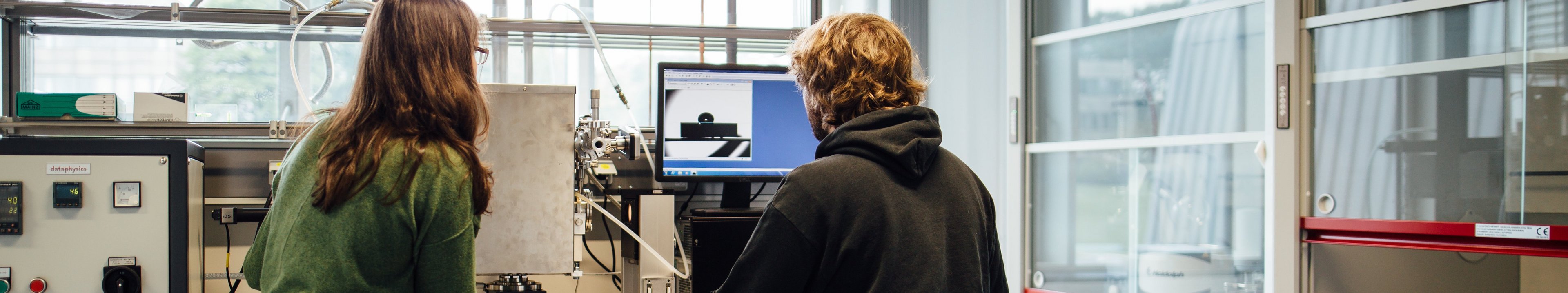 Zwei Personen schauen auf ein Monitor im Labor