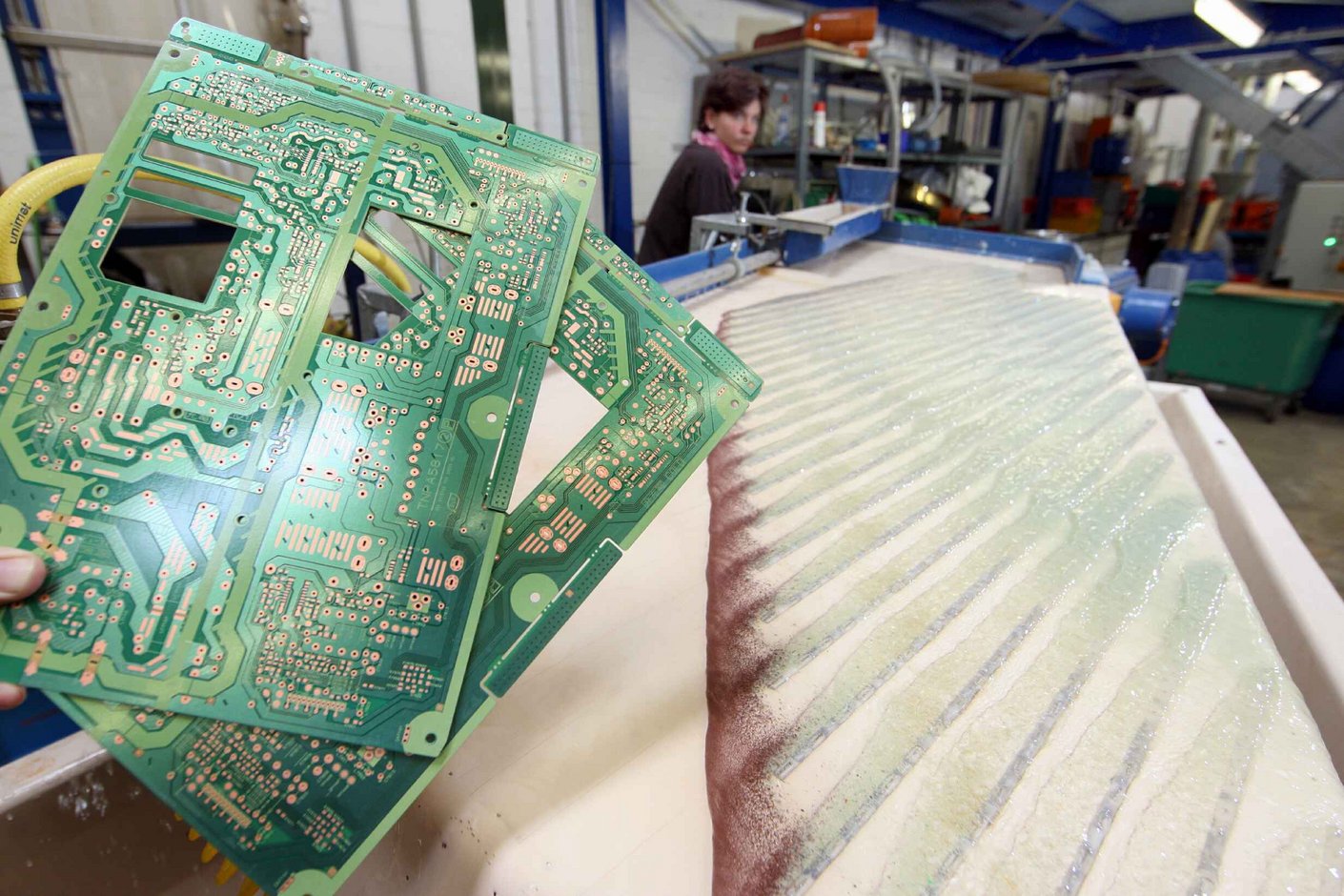 Platinen die neben einer Recyclinganlage ins Bild gehalten werden