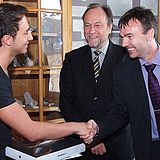 Person erhält ein Macbook und schüttelt einer anderen Person die Hand