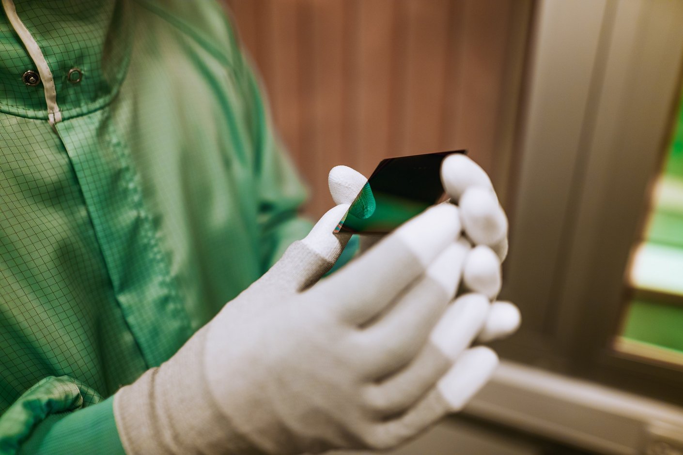 Zwei Hände mit Handschuhen halten eine kleine Glasplatte