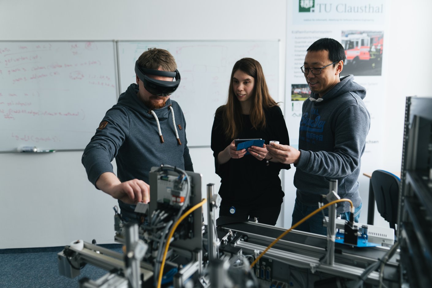 Drei Personen arbeiten an einem Versuch. Eine Person hat eine AR-Brille auf