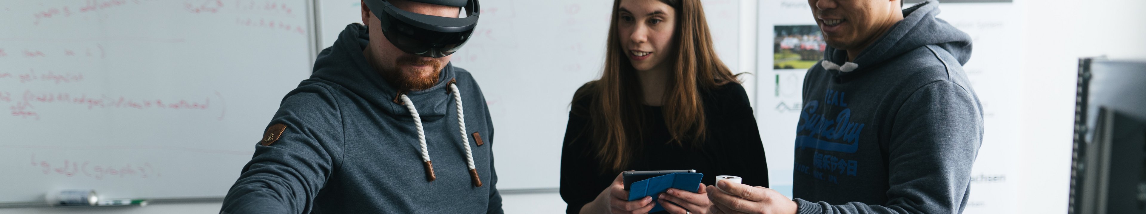 Drei Personen arbeiten an einem Versuch. Eine Person hat eine AR-Brille auf
