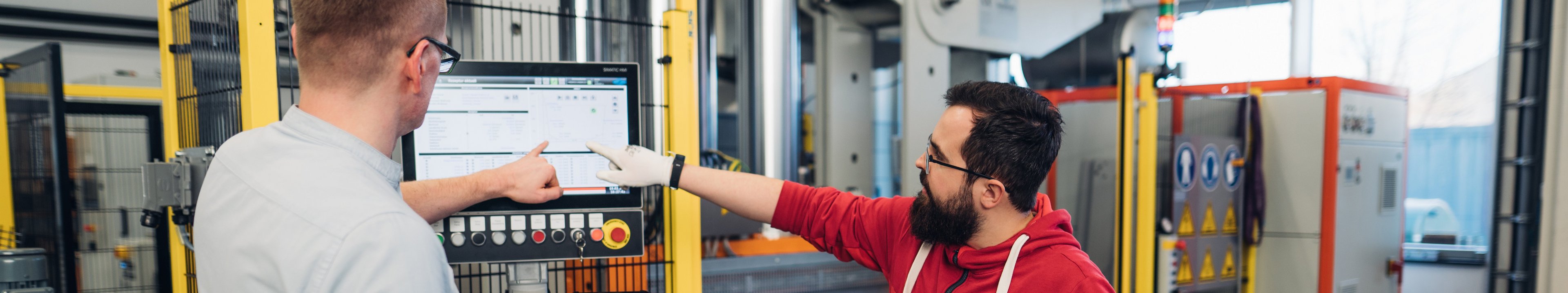 Ein Student und ein Dozent besprechen einen Versuch an einer Maschine.