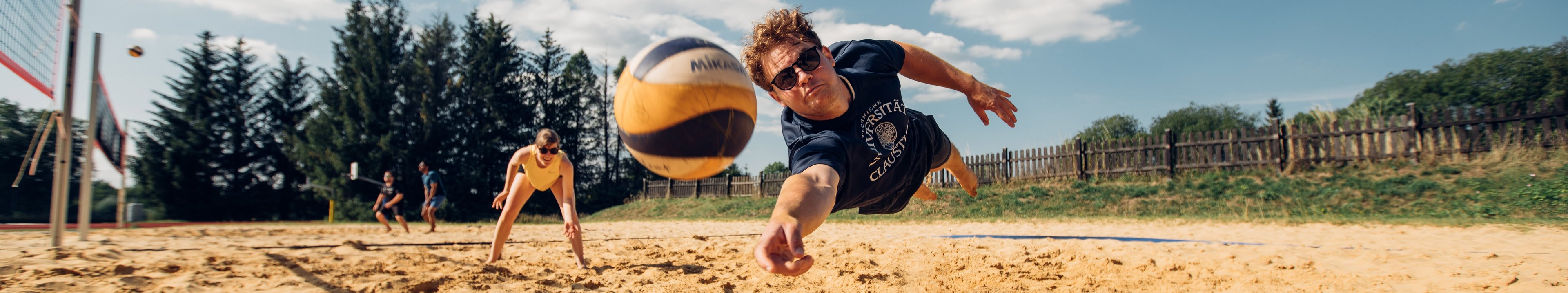 Beachvolleyballer springt einem Ball hinterher