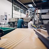 Zwei Personen in einer Werkstatt bedienen eine Maschine