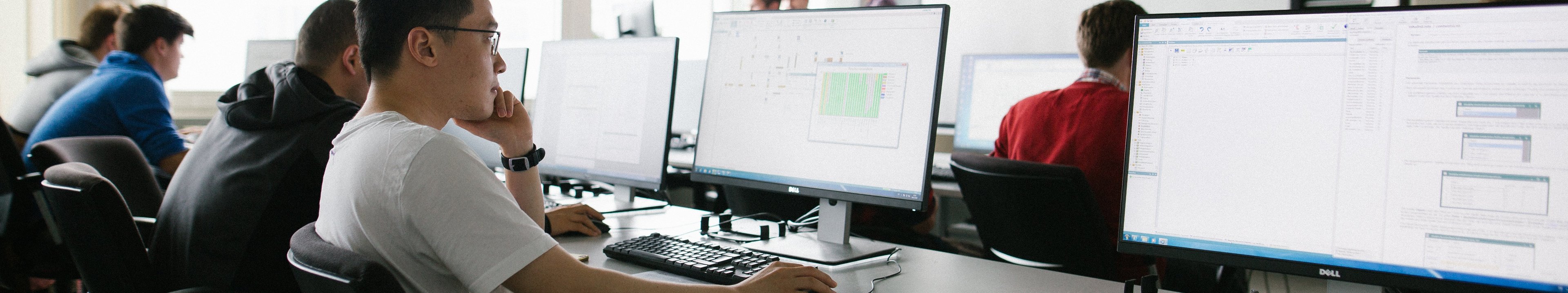 Studierende arbeiten gemeinsam in einerm Computerraum.