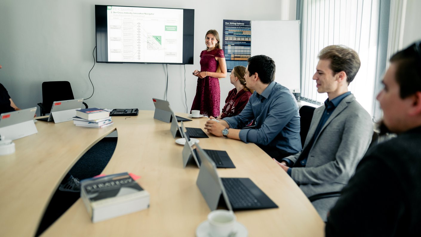 Personen sitzen in einem Seminarraum und hören einer Person zu