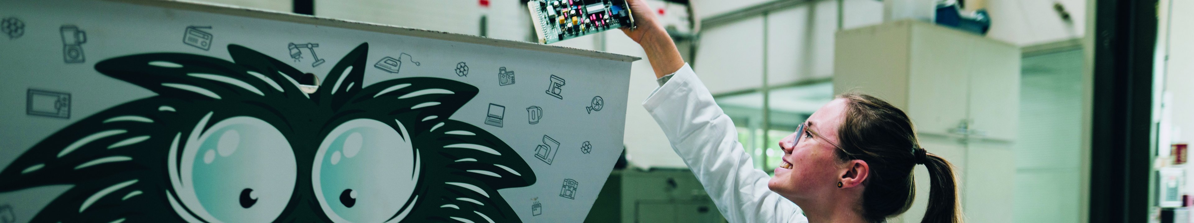 Eine Studentin wirft eine Platine in einen Schredder.