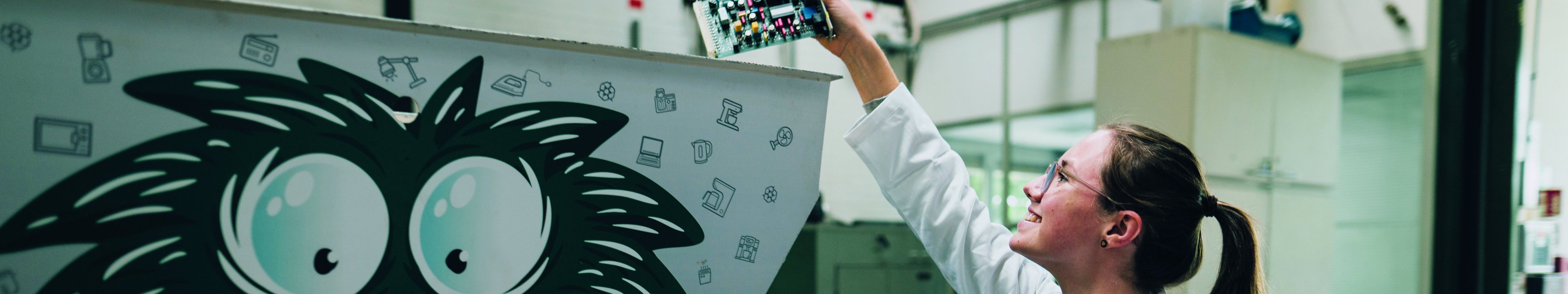 Eine Studentin wirft eine Platine in einen Schredder.