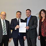 Menschen stehen nebeneinander und halten ein Dokument