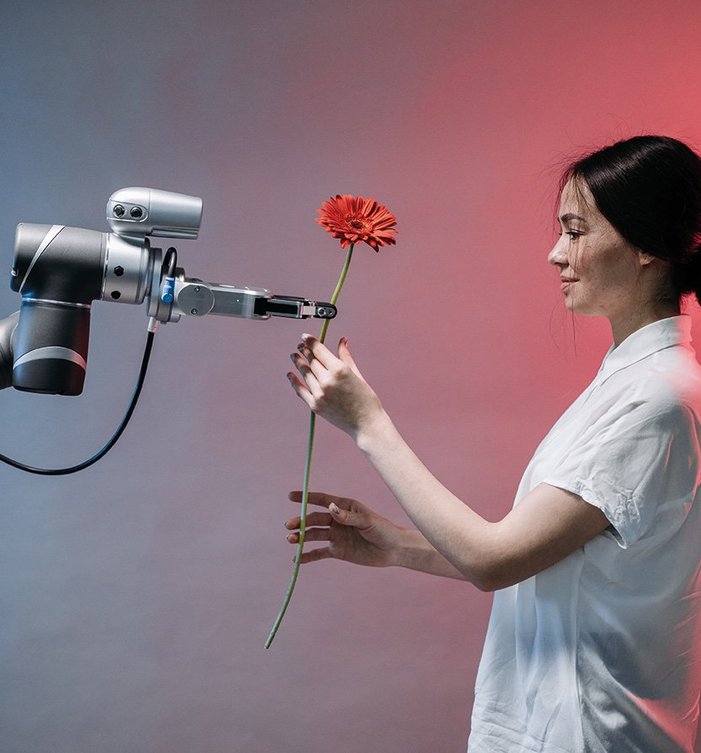 Eine Person nimmt eine Blume aus dem Arm eines Robotors entgegen