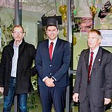 Eine Person trägt den Abschlusshut und steht neben anderen