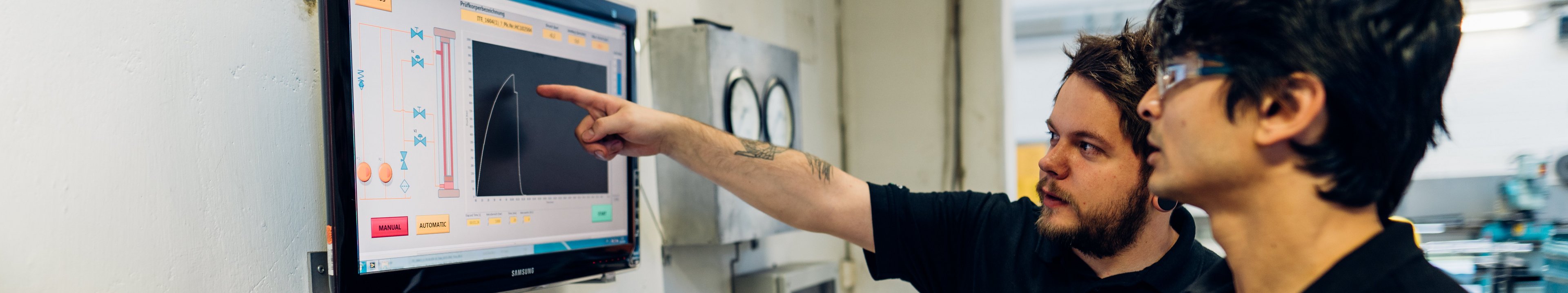 Zwei Personen sprechen über eine Kurve die auf einem Bildschirm angezeigt wird