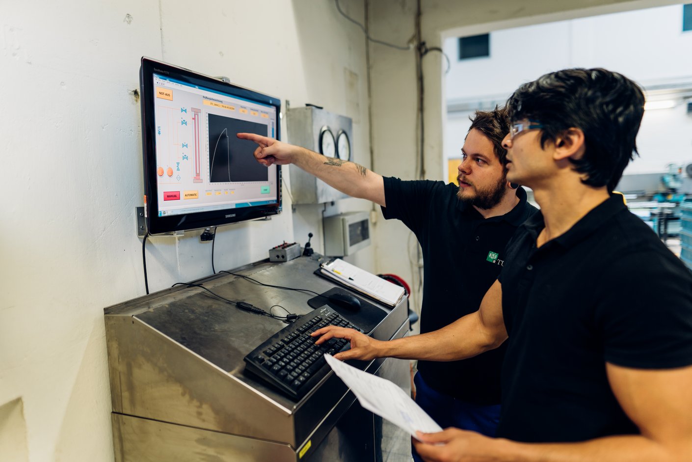 Zwei Personen sprechen über eine Kurve die auf einem Bildschirm angezeigt wird